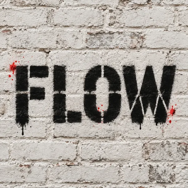 FLOW in black and white stencil graffiti with red accents on pale brick